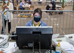 Person with mask on at a computer.
