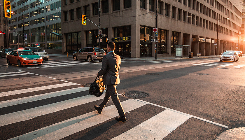 Man in business suit walking on crosswalk in city