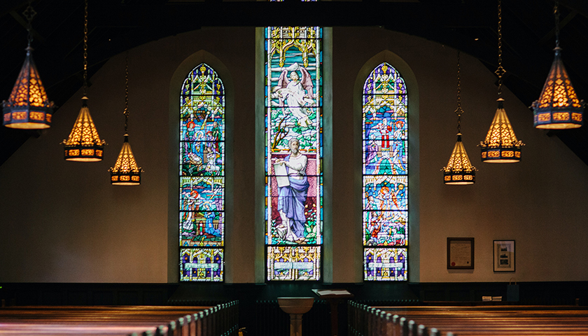 Inside of a church with stained glass and low lighting