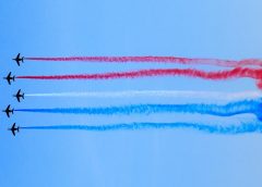 Planes in the sky letting off red, white and blue smoke