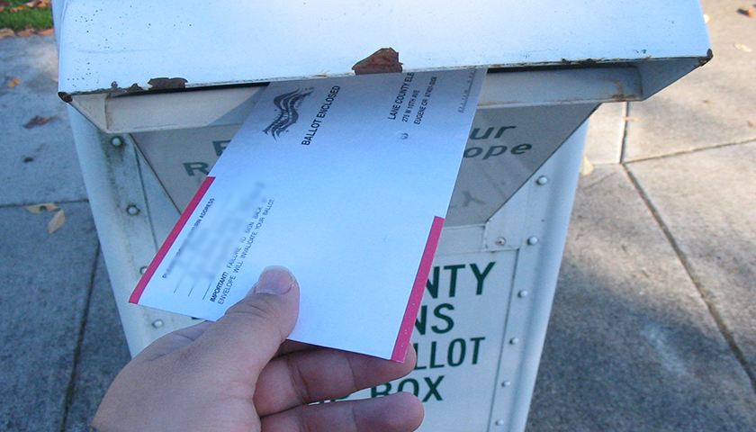 Person putting mail-in ballot in ballot return box