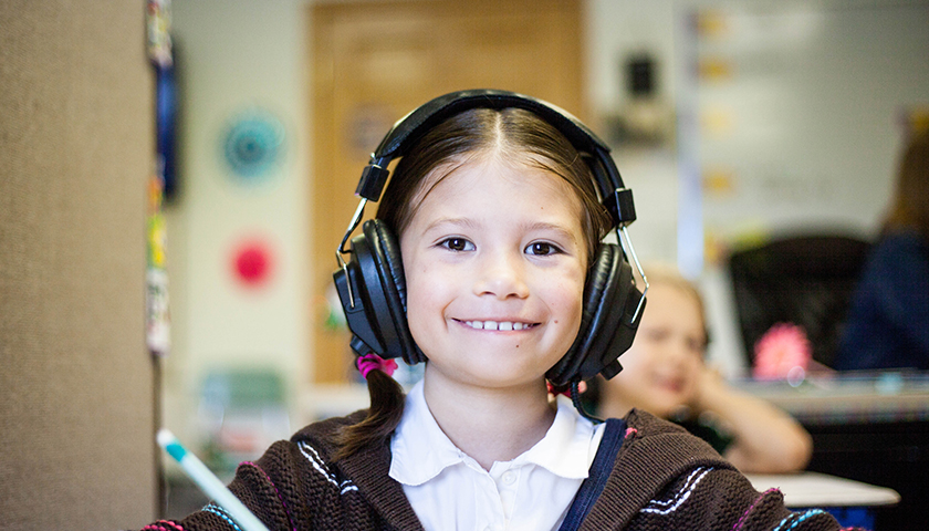 Young girl wearing black headphones, smiling