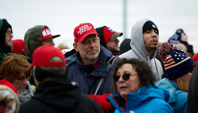 Group of people at a Trump rally, man in a "Keep America Great" hat