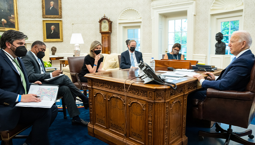 President Joe Biden meets with staff while he talks on the phone with Energy Secretary Jennifer Granholm and energy company executives from areas impacted by Hurricane Ida, Tuesday, August 31, 2021, in the Oval Office of the White House. (Official White House Photo by Adam Schultz)