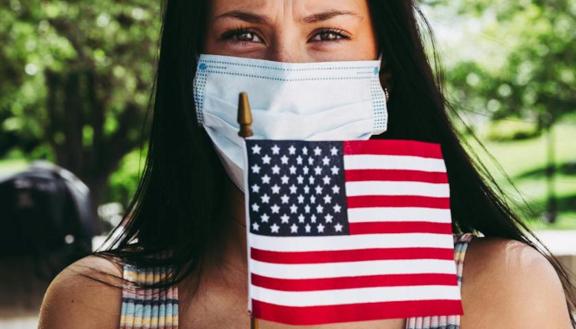 Masked woman holding American flag