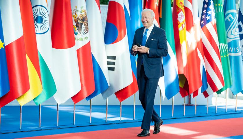 President Biden walking in front of a line of international flags